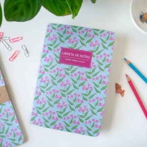 Libreta de notas copihuito vista superior en un escritorio, rodeada de lápices y clips, incluye flora nativa de Chile