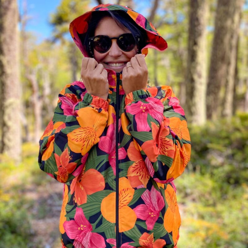 Persona usando cortaviento Astromelias en el bosque, sonriendo, con diseño de flora nativa de Chile, vista frontal